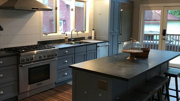 A modern kitchen with a central island, stainless steel appliances, and a large window. - Updated Middlebury Home! Walk to Town, Sleeps Groups Comfortably (Middlebury)