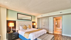 Une chambre à coucher avec un grand lit, des tables de chevet avec des lampes, un miroir et une porte donnant sur une salle de bain.