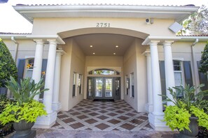 Classic entrance with a symmetrical design, featuring a central doorway and two sets of columns, surrounded by lush greenery.