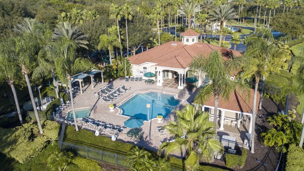 An aerial view of a resort with a swimming pool, lounge chairs, and palm trees.