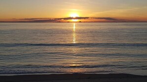Une scène de plage avec un coucher de soleil sur l’eau.