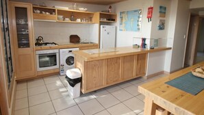 Une cuisine compacte avec des meubles de rangement en bois, une cuisinière à gaz, un lave-linge et un réfrigérateur.
