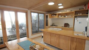 Une cuisine avec des meubles en bois, un plan de travail et une vue à travers les portes vitrées.