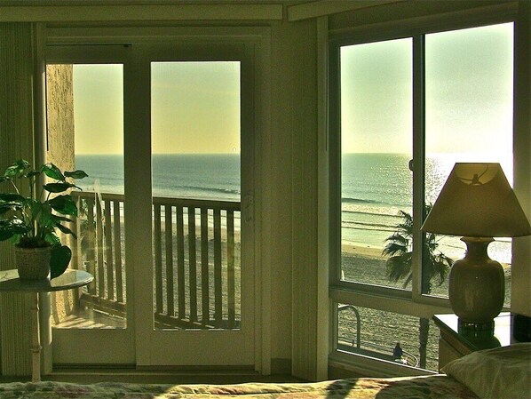 A room with a view of the ocean through large windows, a potted plant, and a lamp on a bedside table. - Panoramic Oceanfront Views - Penthouse (SAN DIEGO)