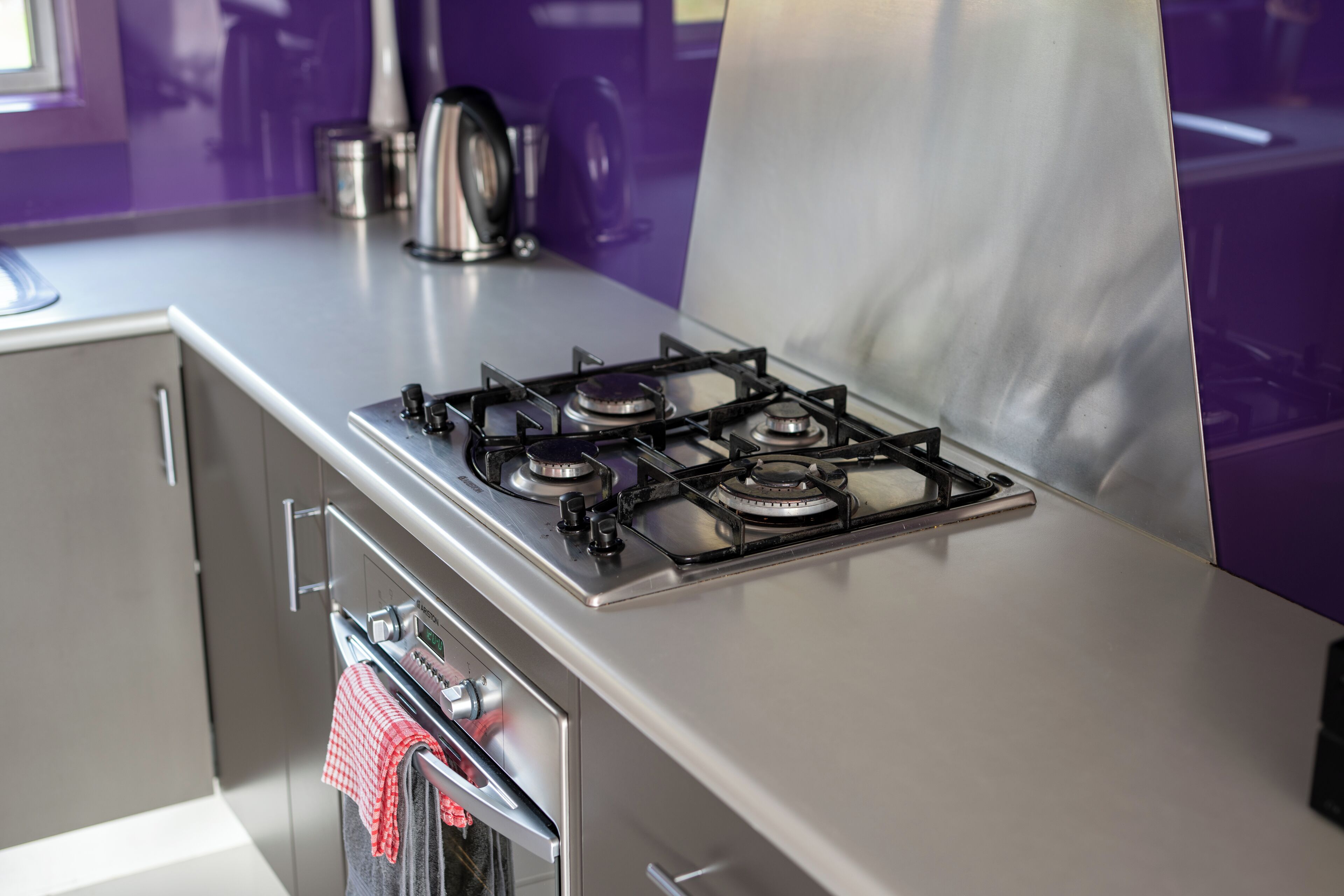 Eine Küche mit einem Edelstahlherd, Backofen und einem rot-weißen karierten Handtuch, das am Backofen hängt.