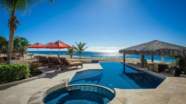A pool area with a view of the ocean, lounge chairs, and umbrellas. - 2 FREE NIGHTS IN CABO at Casa Alcini! (Cabo San Lucas)