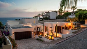 A modern coastal property with multiple buildings, a cobblestone driveway, and a view of the ocean. - 2 FREE NIGHTS IN CABO at Casa Alcini! (Cabo San Lucas)