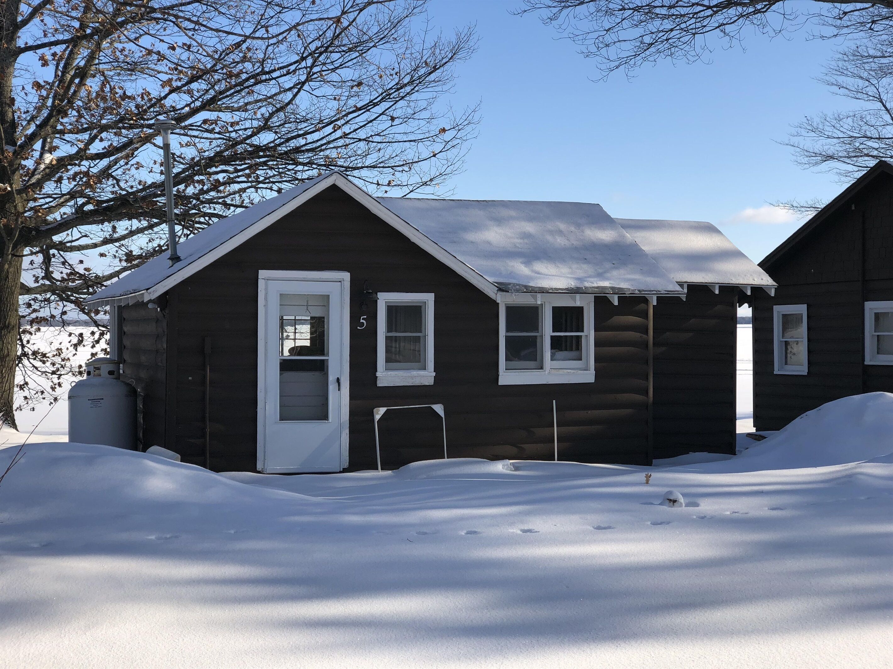 A log cabin with a white door and windows, surrounded by snow.
