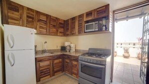 A kitchen with wooden cabinets, a white refrigerator, a microwave, a stove, and a sink. - Rincon Del Almendro 1BD Studio for rent in Old Town, Puerto vallarta (Puerto Vallarta)
