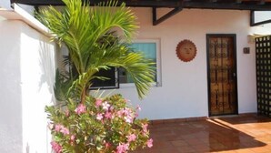 A building with a tiled roof, a door with decorative metalwork, and a potted plant with pink flowers. - Rincon Del Almendro 1BD Studio for rent in Old Town, Puerto vallarta (Puerto Vallarta)