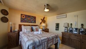 A bedroom with a bed, a nightstand, a dresser with speakers, and a painting on the wall. - Rincon Del Almendro 1BD Studio for rent in Old Town, Puerto vallarta (Puerto Vallarta)
