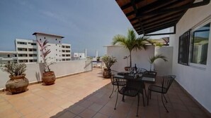 A rooftop terrace with a dining area, potted plants, and a view of surrounding buildings. - Rincon Del Almendro 1BD Studio for rent in Old Town, Puerto vallarta (Puerto Vallarta)