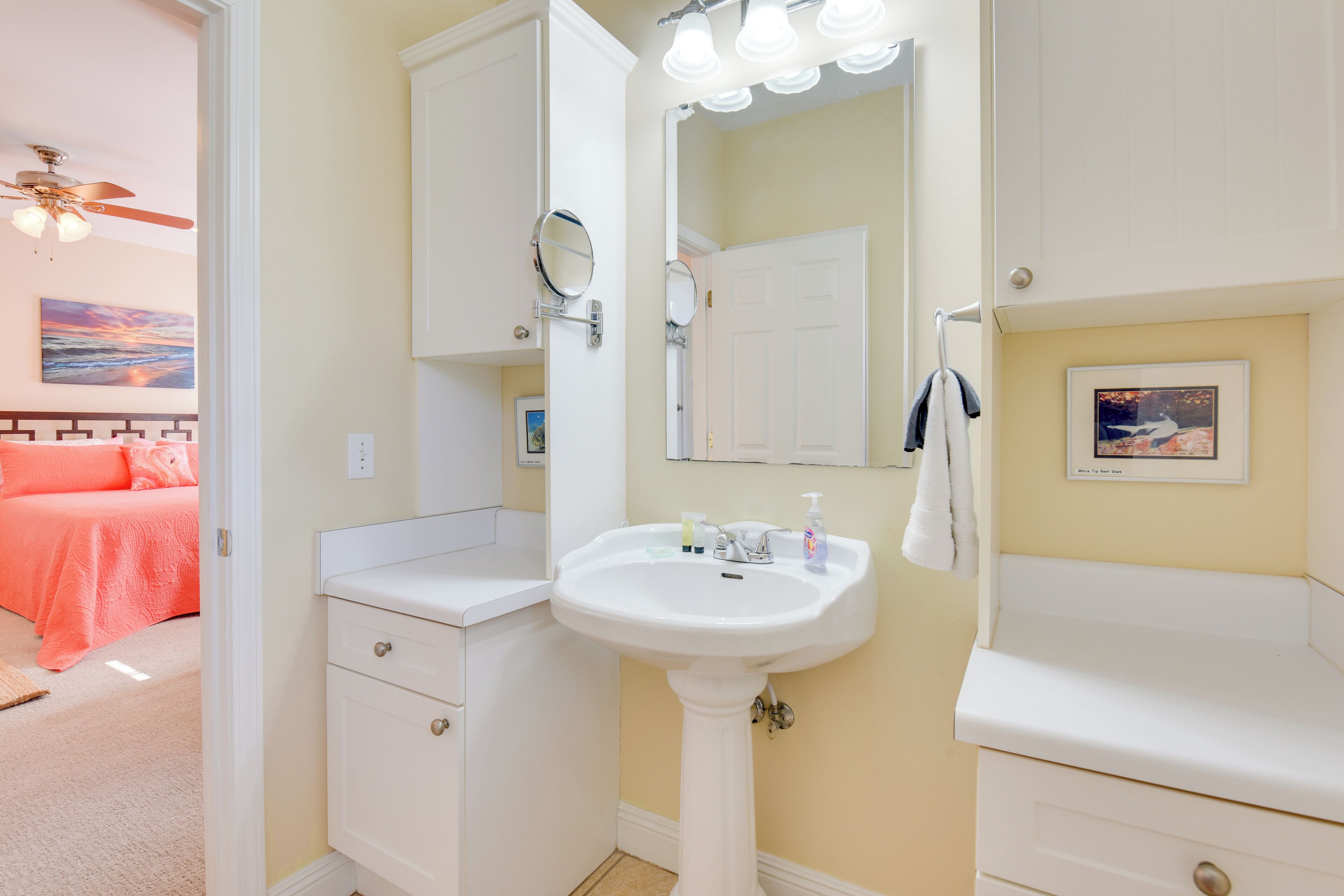 Une salle de bain avec un lavabo sur colonne, un meuble-lavabo et un ventilateur de plafond.