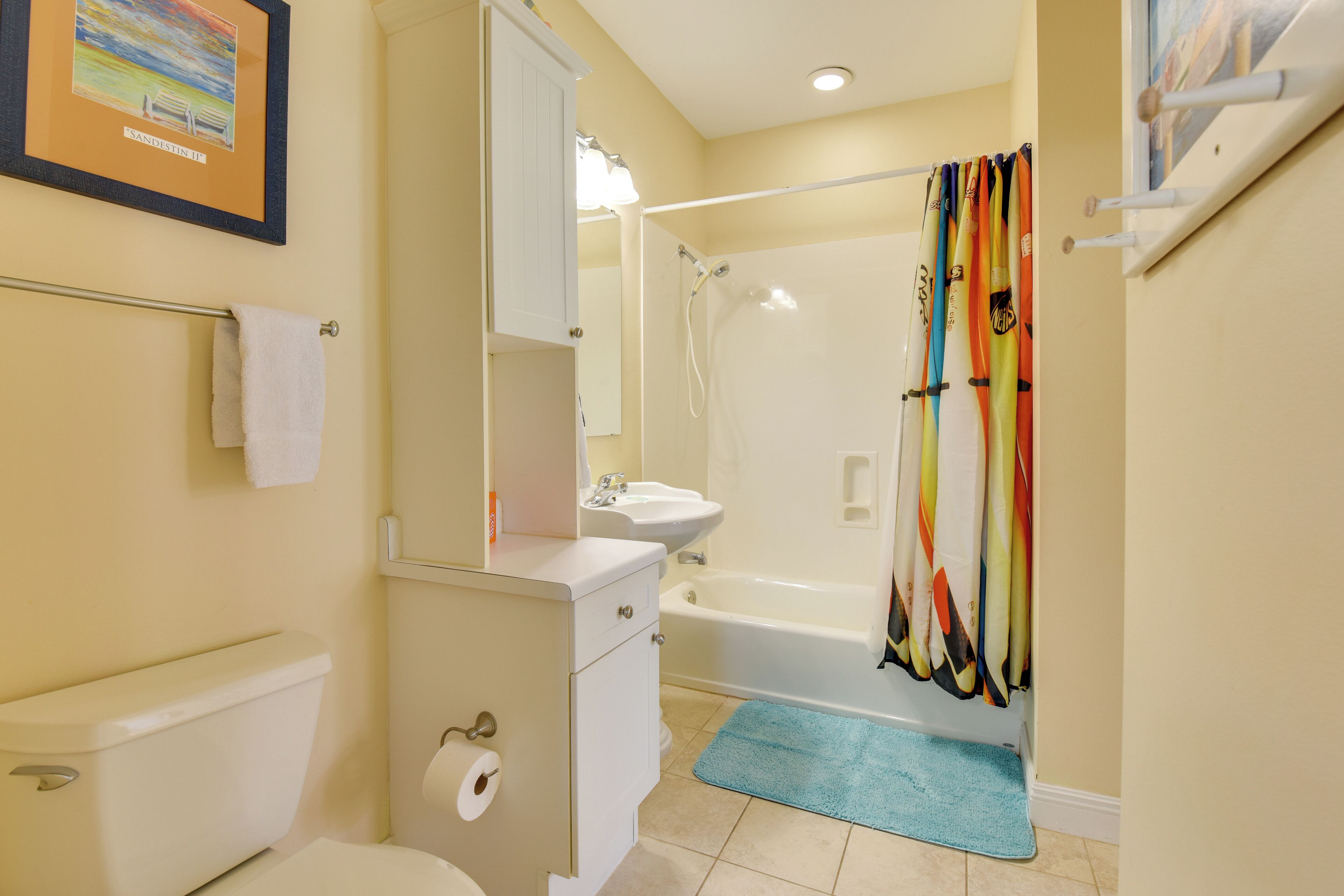 A bathroom with a toilet, sink, mirror, and shower curtain.