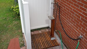 A wooden deck with a white fence leading to a brick wall.