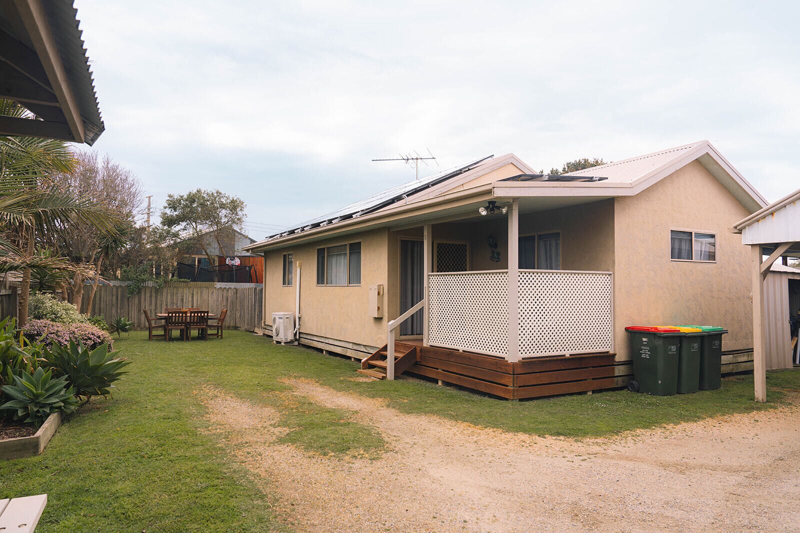 A single-story mobile home with a porch, a fenced backyard, and a patio area.