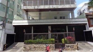 A multi-story building with a gated entrance, a motorcycle parked in front, and a clear sky. - MAKE YOURSELF AT HOME! Spacious, 4 bedrooms, air conditioning, free Wi-Fi, close to the street market! (Cabo Frio)