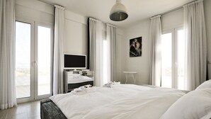 Ein Hotelzimmer mit einem großen Bett, einem Flachbildfernseher, einem kleinen Tisch und Blick ins Freie.