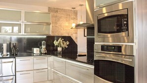 Una cocina moderna con electrodomésticos de acero inoxidable, una encimera negra y armarios blancos.