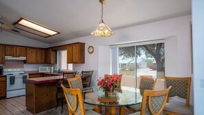 Una cocina moderna con armarios de madera, una mesa de comedor de vidrio y una araña.