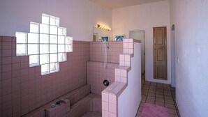 Un baño con ducha, lavamanos y ventana.