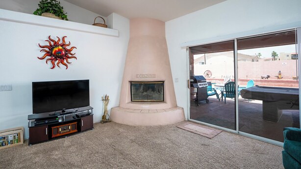Una sala de estar con una televisión de pantalla plana, una chimenea y un ventanal corredizo que da a un patio exterior.