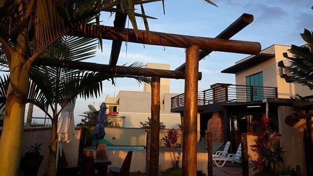 Terraço no telhado com piscina, palmeiras e estrutura de edifício moderno.