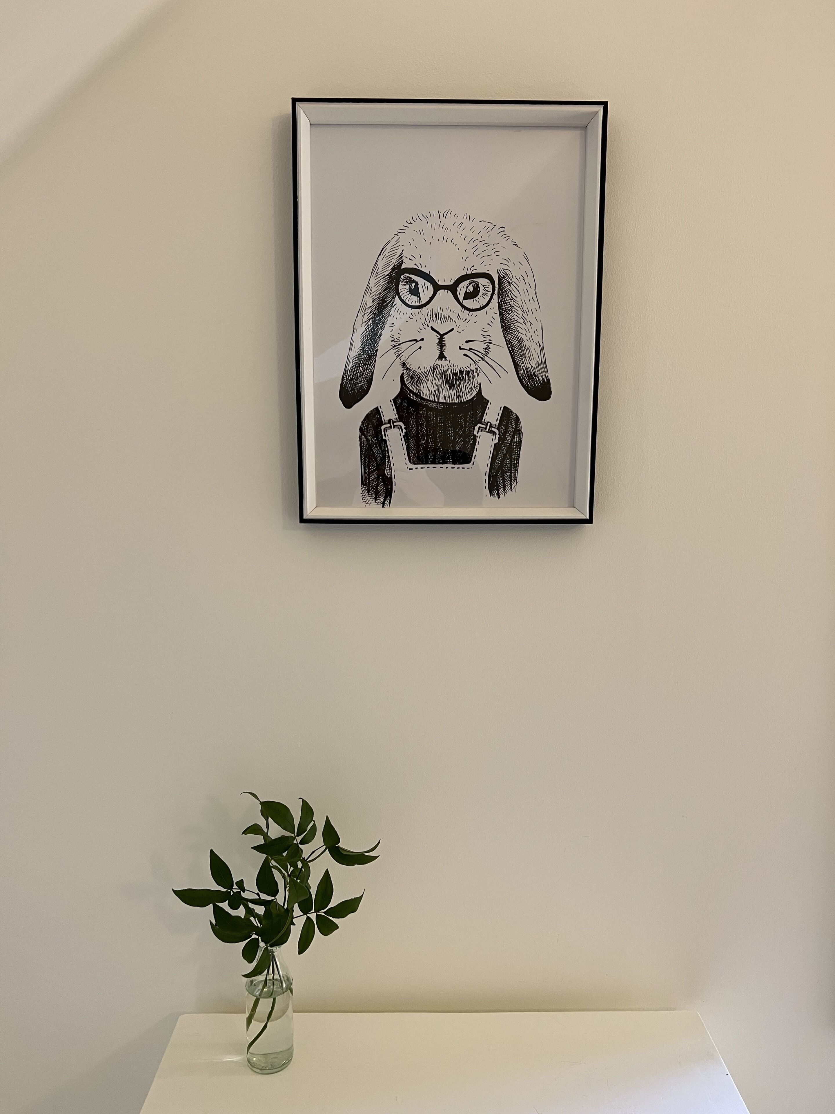 A framed black and white illustration of a rabbit on a wall.