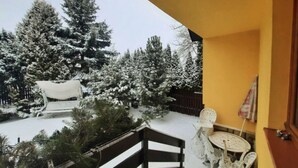 Un balcón con vistas a árboles cubiertos de nieve y un edificio al fondo.
