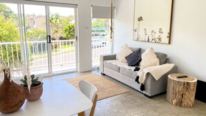 A modern living room with a grey sofa, a white table, and a large window. - Salt by the sea unit 3 (Port Macquarie)
