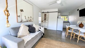 A modern living room with a grey sofa, a large mirror, and a ceiling fan. - Salt by the sea unit 3 (Port Macquarie)