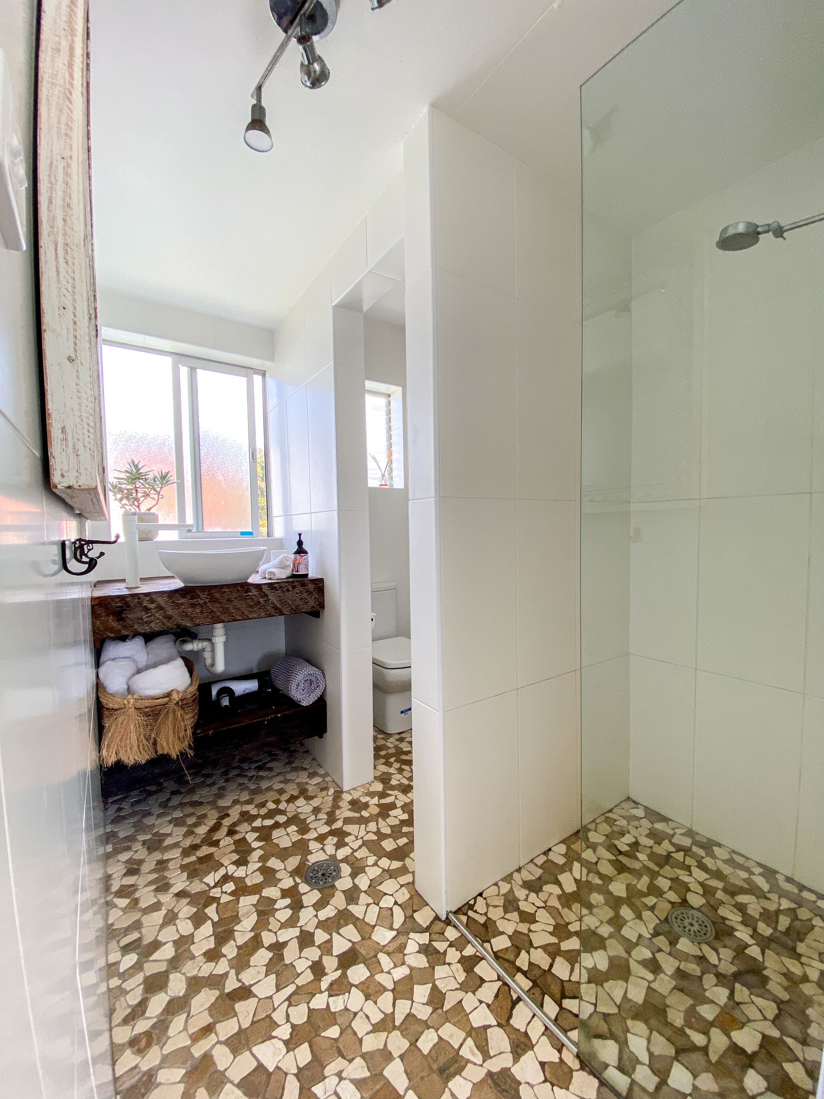 A bathroom with a mosaic floor, a sink with a towel rack, and a shower area.