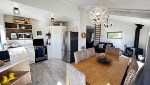 Eine moderne Küche mit weißen Schränken, einem Edelstahlkühlschrank und einem Essbereich mit Holztisch und gewebten Stühlen.