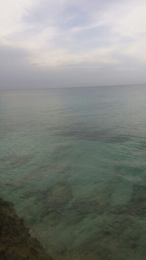 Blick auf ein ruhiges Meer mit klarem Wasser und einer fernen Küste.