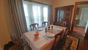 Une salle à manger avec une table dressée pour six personnes, comprenant assiettes, couverts et un centre de table composé d’oranges.