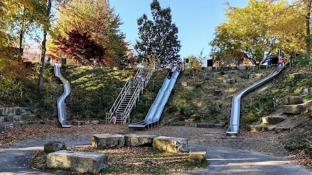 Un parc avec un toboggan et des escaliers en métal.