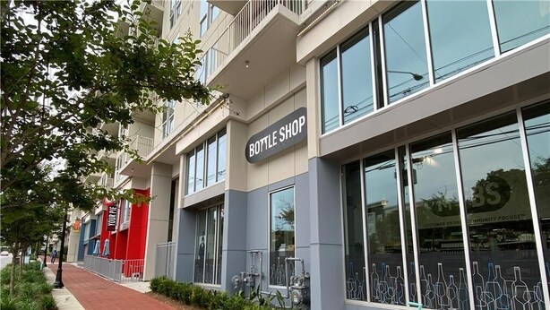 Un edificio con un letrero que dice 'BOTTLE SHOP', ventanas amplias y una bicicleta estacionada afuera.
