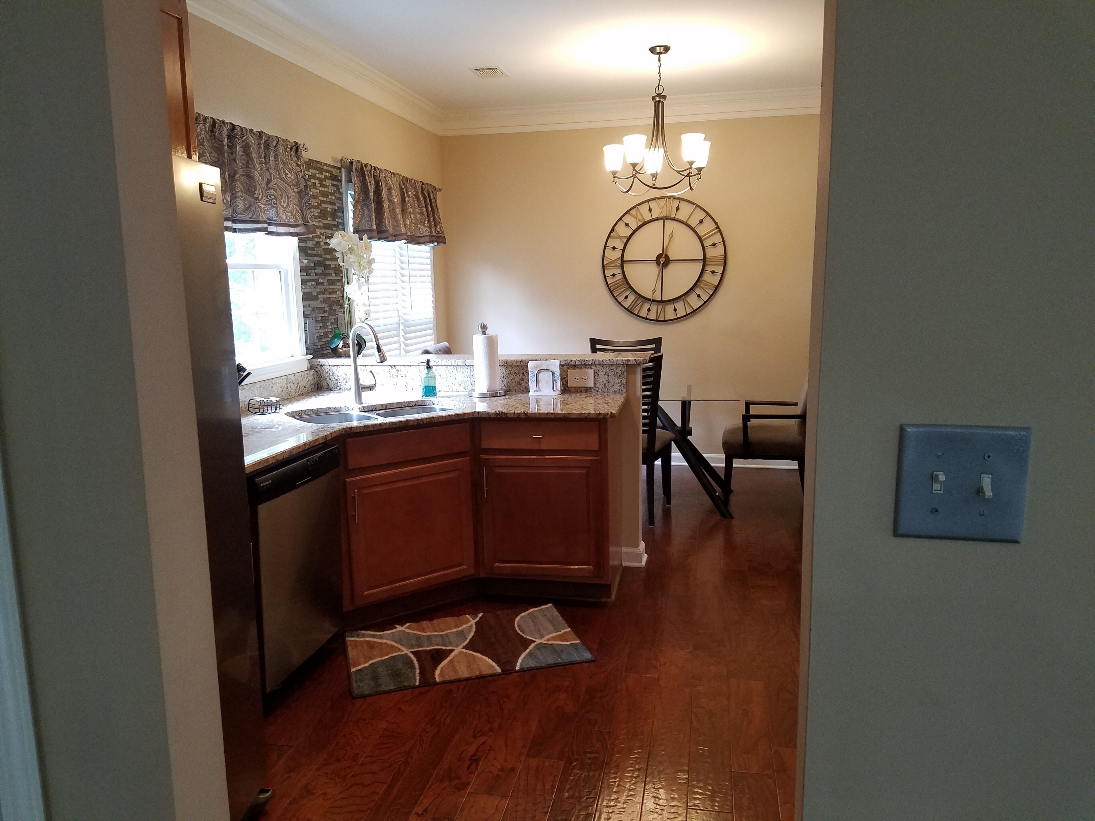 A kitchen with wooden cabinets, a granite countertop, a built-in dishwasher, a sink, and a chandelier.