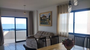 A dining area with a table, chairs, a vase of flowers, and a painting on the wall.