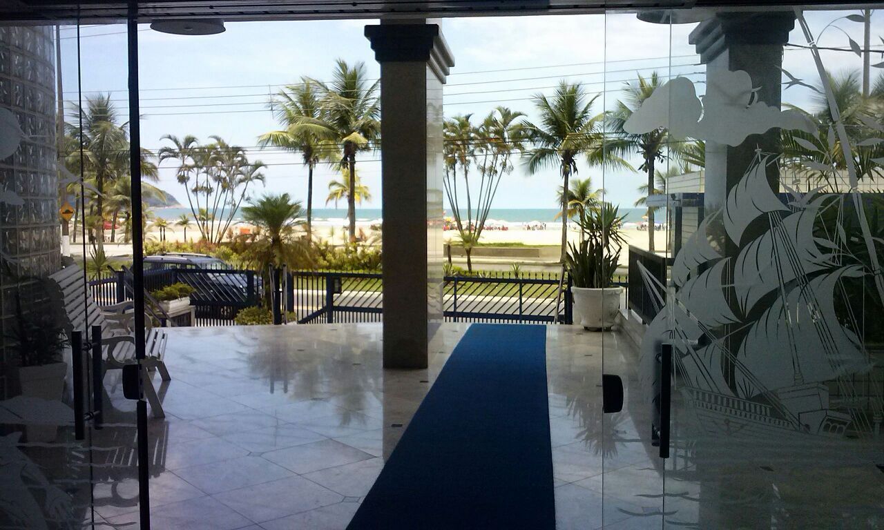 Vista desde un edificio hacia una playa con palmeras y cielo despejado.