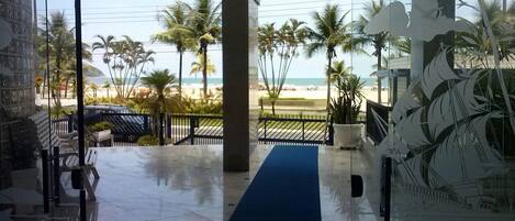 Vista desde un edificio hacia una playa con palmeras y cielo despejado.