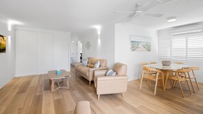Un salon moderne comprenant un canapé, une table basse et un coin repas avec des chaises.