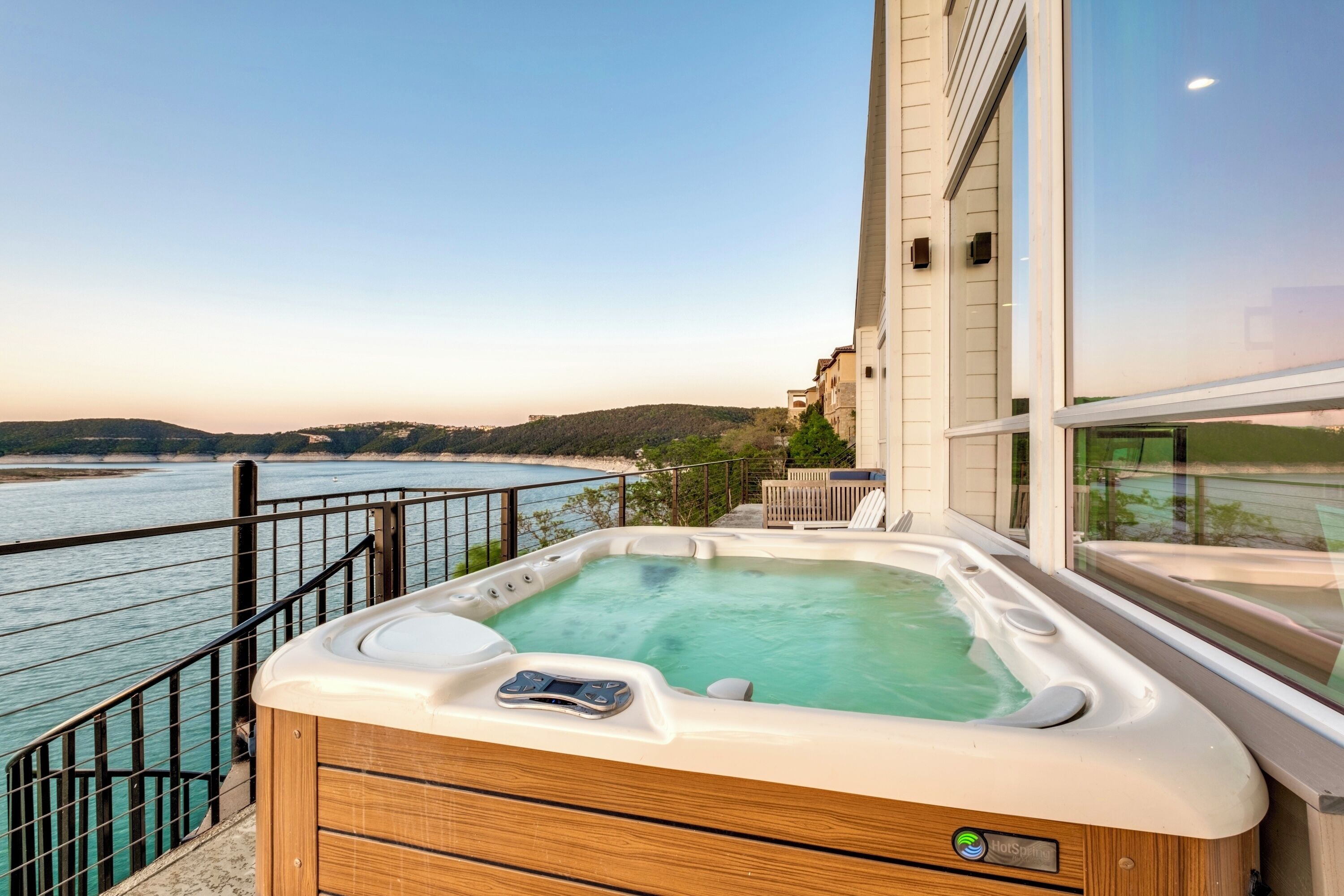 A hot tub on a balcony with a view of the sea and hills.