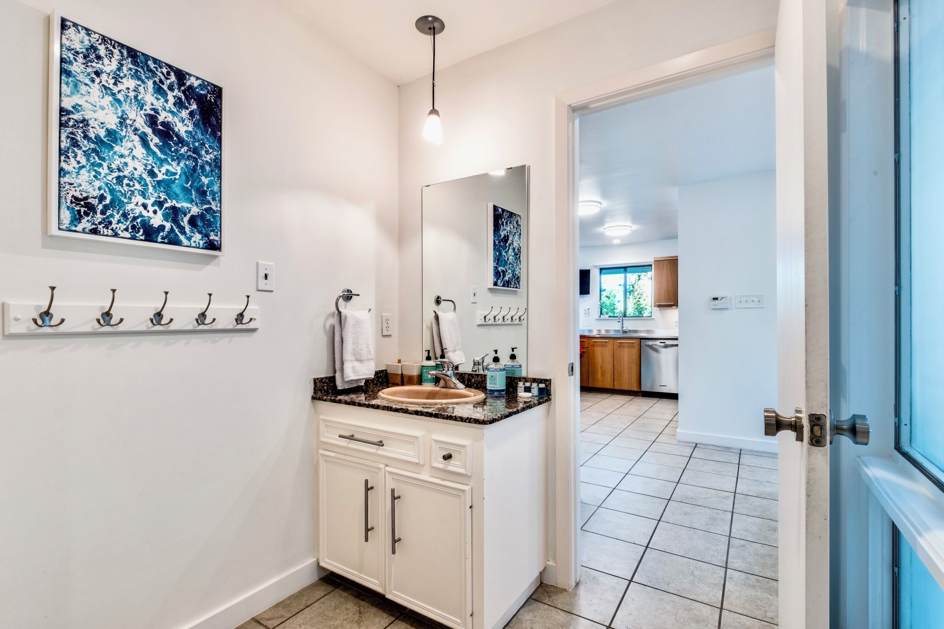 Une salle de bain moderne avec un grand miroir, un lavabo avec un plan de travail et un porte-serviettes fixé au mur.