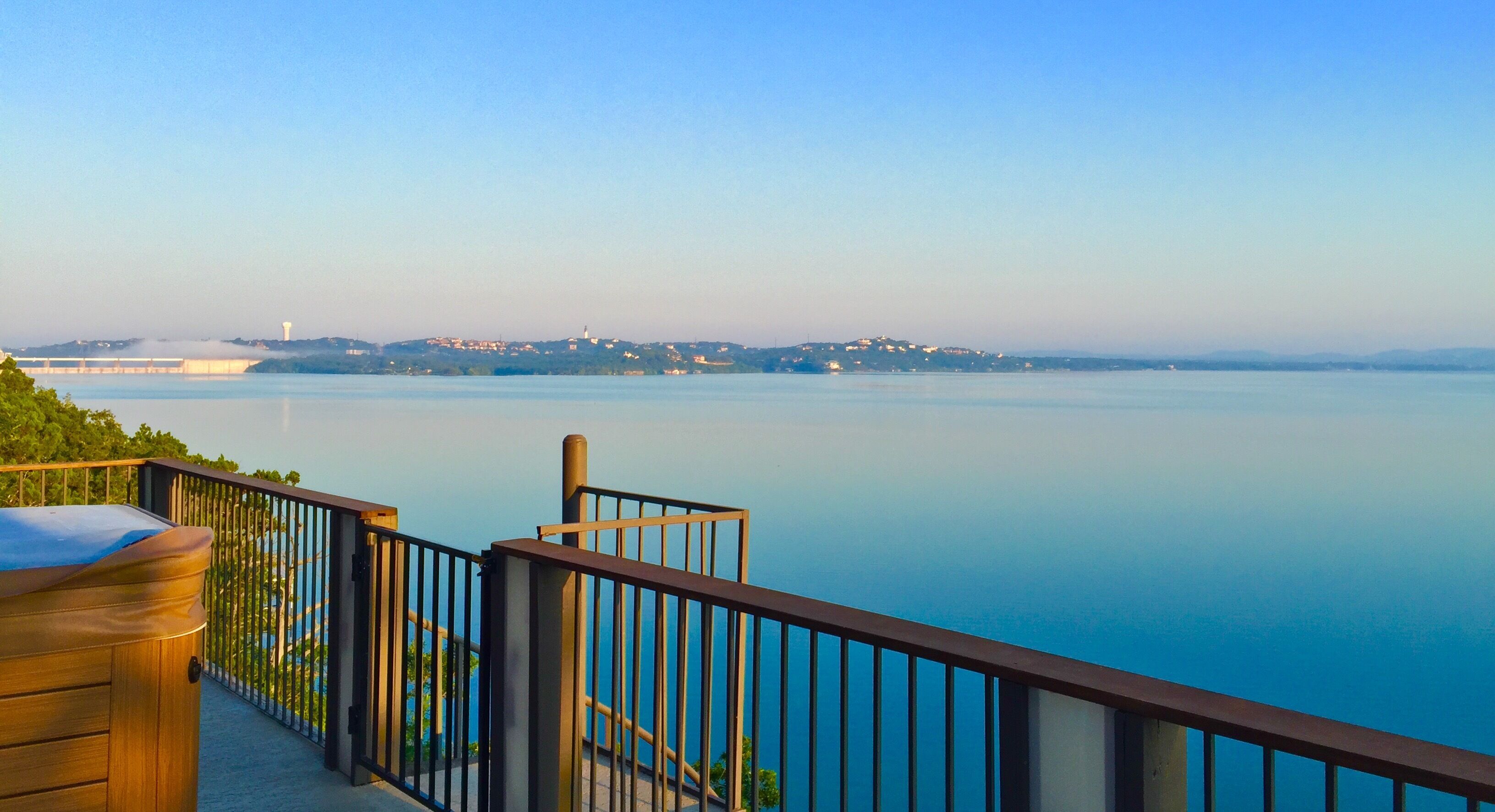 A waterfront balcony with a view of a calm lake and distant buildings.