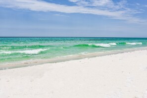 Een strand met helder turquoise water en wit zand.