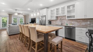 Una cocina moderna con armarios blancos, una mesa de comedor de madera y un horno empotrado.
