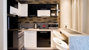 Una cocina compacta con armarios blancos, protector contra salpicaduras de piedra, microondas y cafetera.