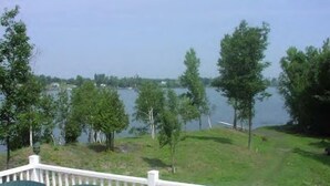 A deck with a view of a lake, surrounded by trees. - BLOW OUT-SALE PRICES!  3 DAY FOLIAGE,Fishing, Dock, Fire Pit, Boat launch & Boat (North Hero)