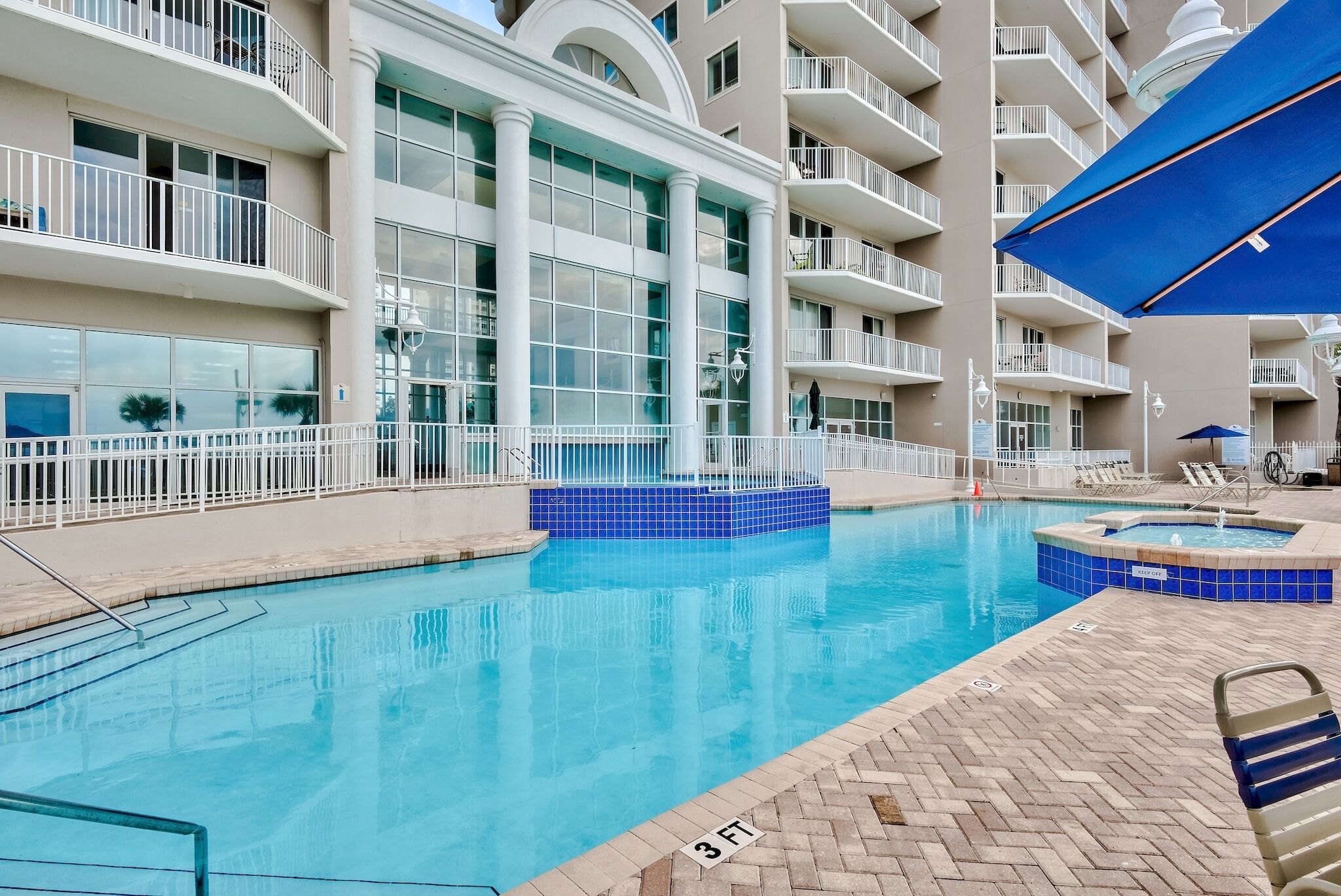 A swimming pool with a 3 FT depth marker, surrounded by a brick deck and white railings.